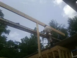 Carpenter setting a ridge beam over a new addition frame — Ice Dam Removal by Roofing Brothers in Avon