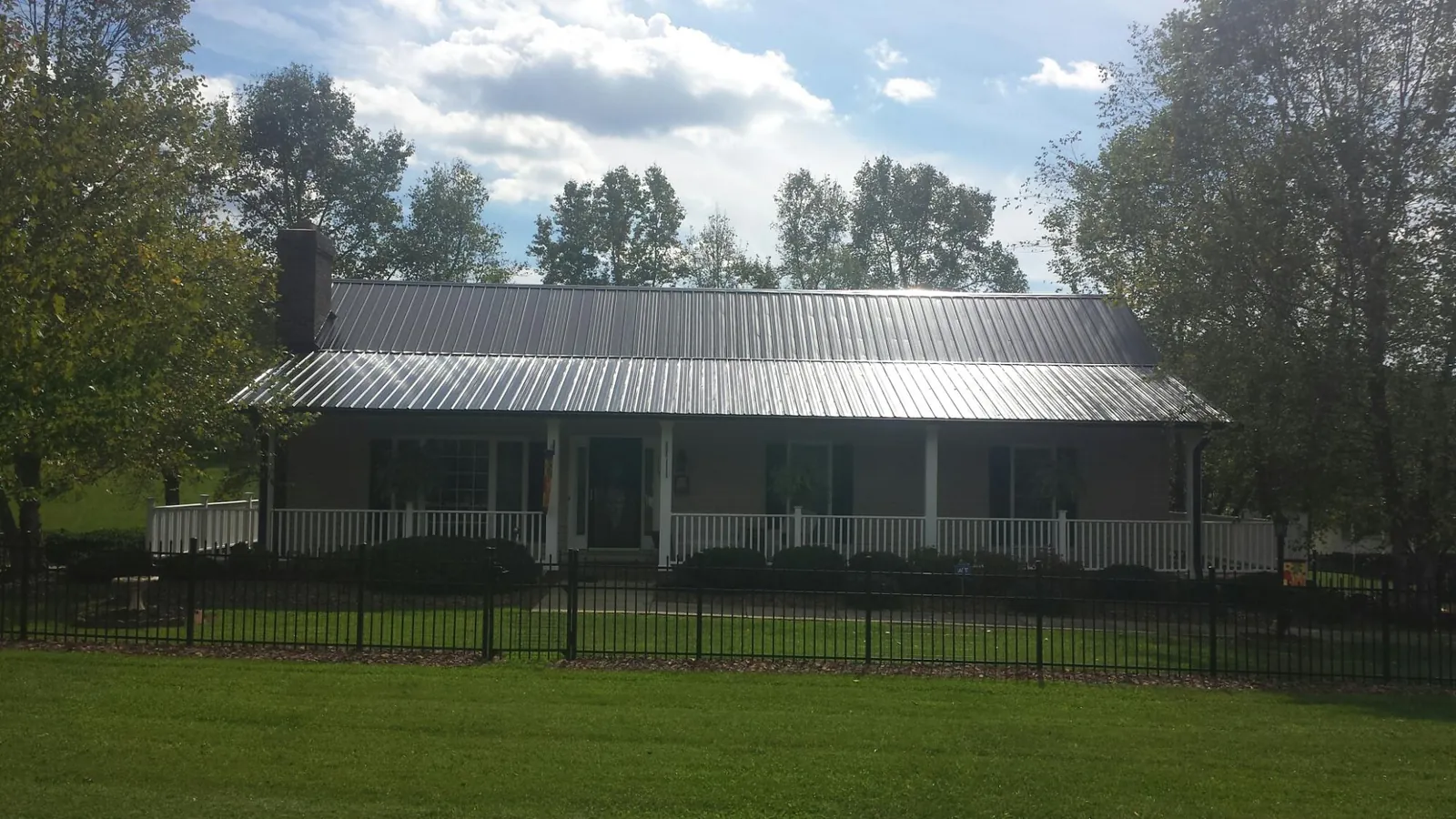 Gray metal roof on a brick ranch with a full width front porch — Gutter Guard Installation work by our crew in Avon
